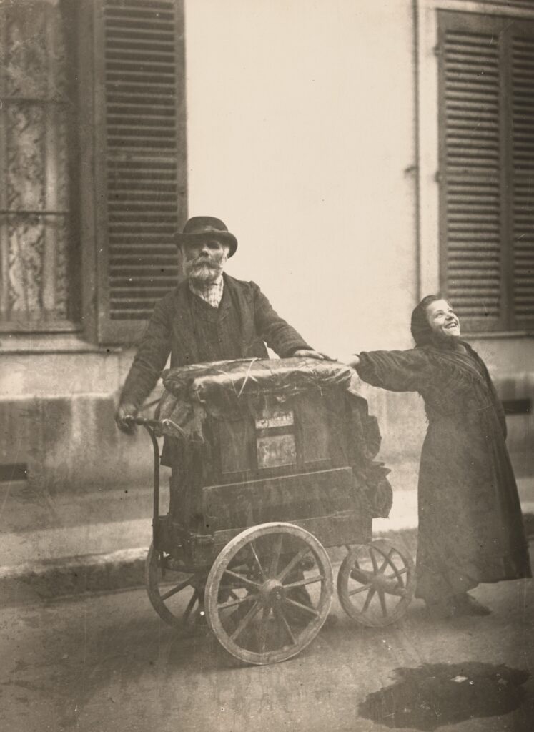 Eugène Atget photograph Joueur d'orgue, an organ grinder and a singing woman on a Paris street, 1898 to 1899